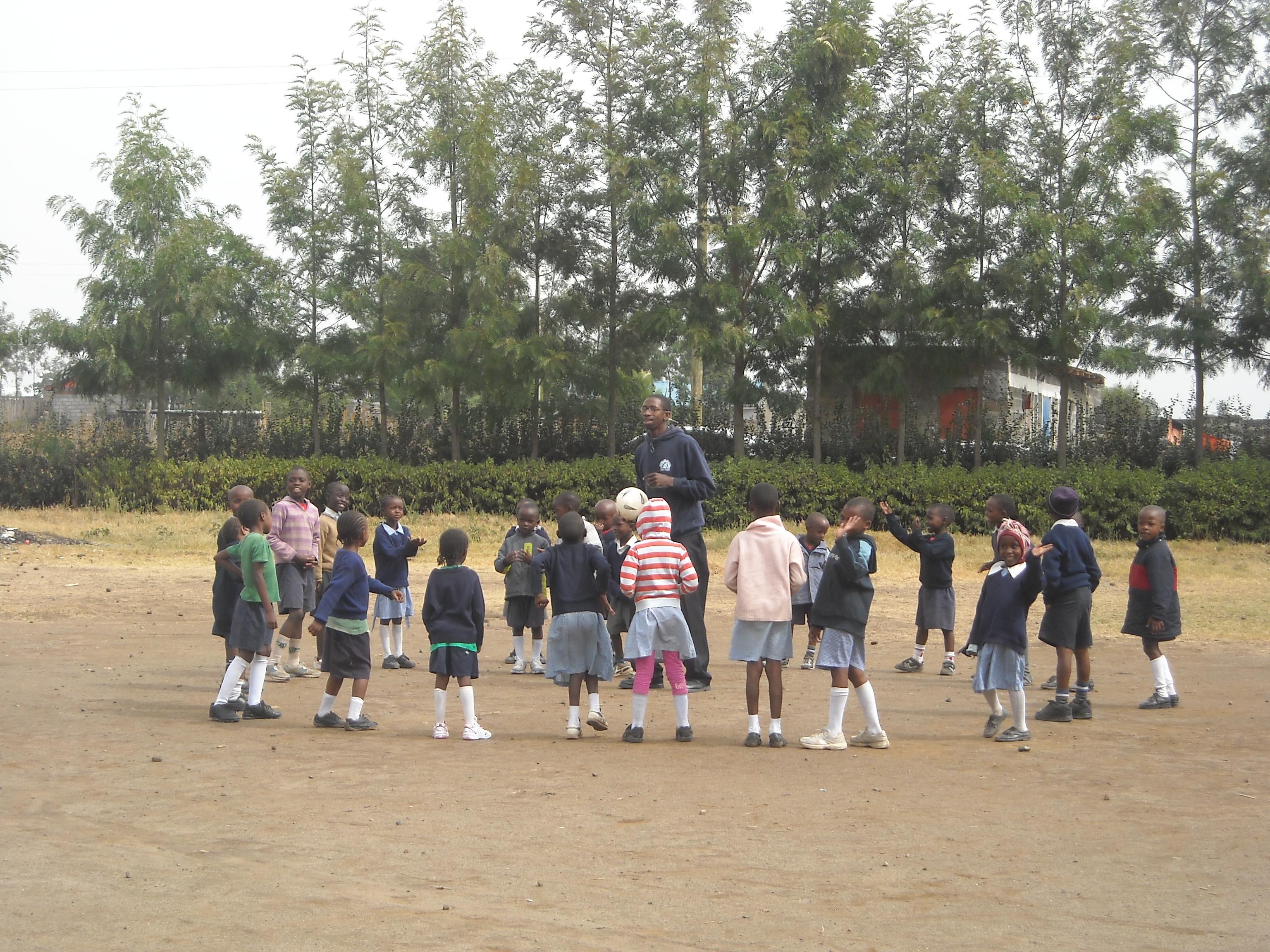 Projects Abroad volunteers organise an outdoor activity with their students during their teaching work experience in Kenya Volunteers and students stand in a circle while playing a game at the volunteer teaching placement in Kenya